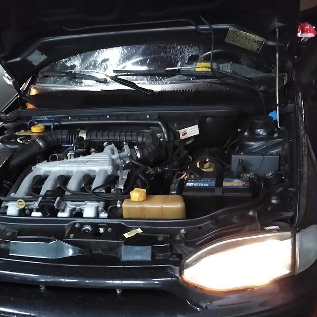 Motor de carro com capô aberto e faróis acesos na oficina